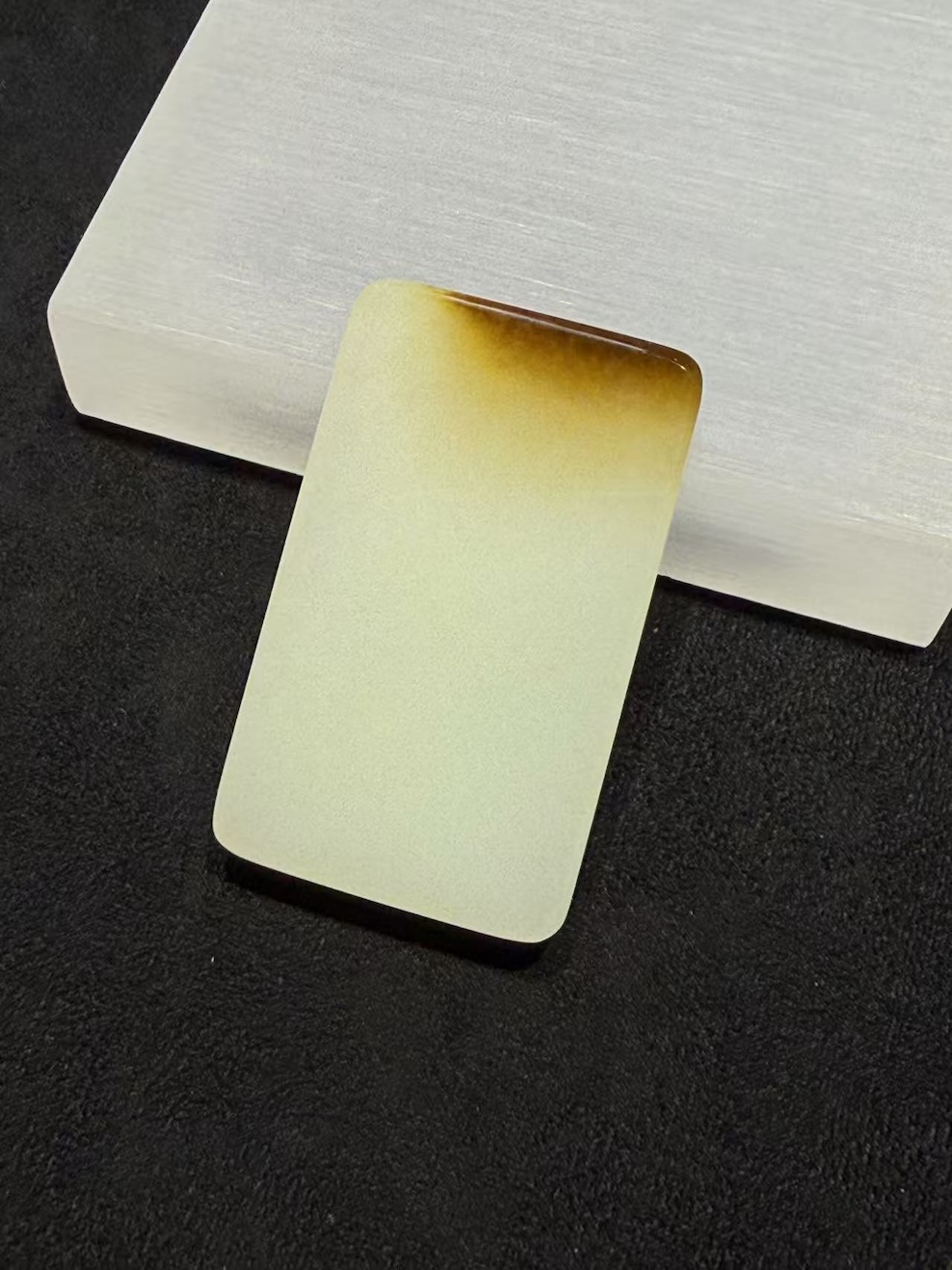 Uncarved white nephrite jade pendant with amber top