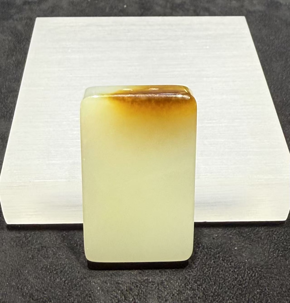 Uncarved white nephrite jade pendant with amber top