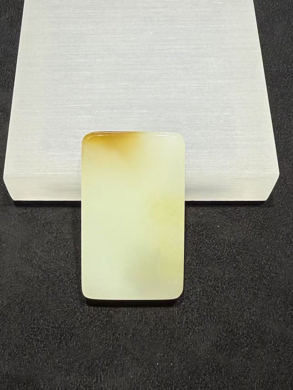 Uncarved white nephrite jade pendant with amber top