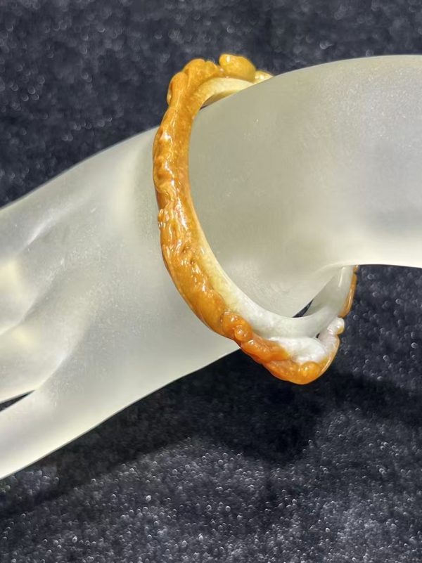 Translucent brownish-yellow jadeite bangle with hand-carved ruyi cloud scroll motifs symbolising fortune and continuity — Nanyang Jade Singapore