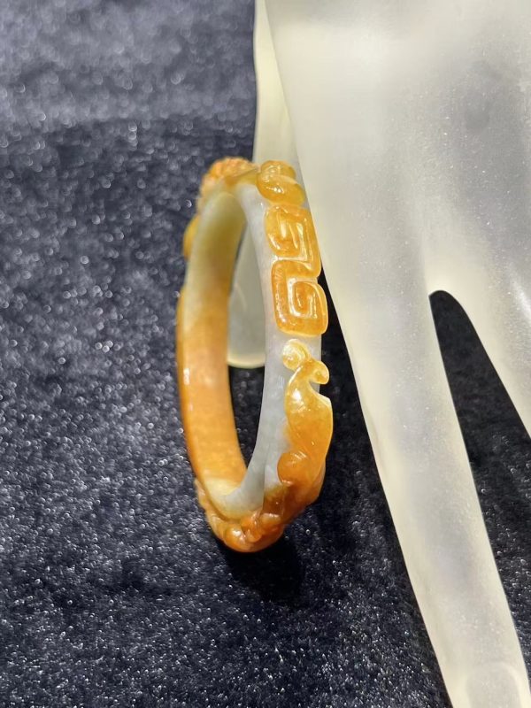 Translucent brownish-yellow jadeite bangle with hand-carved ruyi cloud scroll motifs symbolising fortune and continuity — Nanyang Jade Singapore