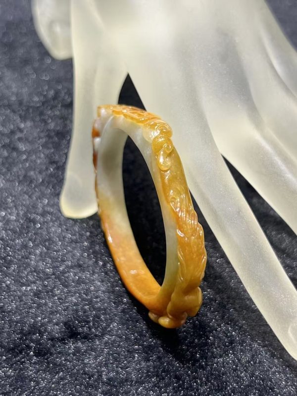 Translucent brownish-yellow jadeite bangle with hand-carved ruyi cloud scroll motifs symbolising fortune and continuity — Nanyang Jade Singapore