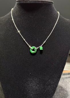 Translucent green jadeite safety knot pendant with dangling jade barrel on 18K white gold chain symbolising peace and protection — Nanyang Jade Singapore