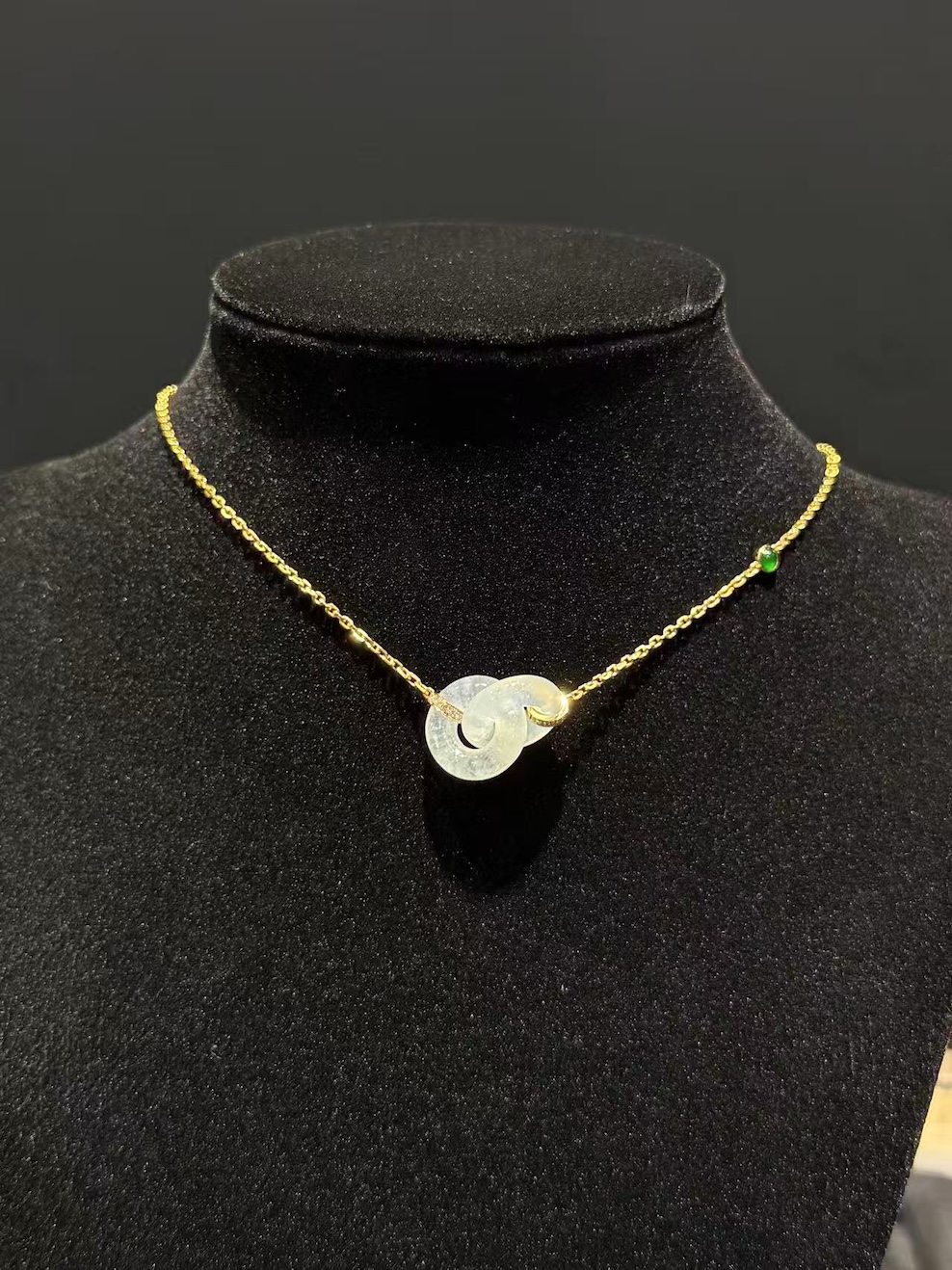 Icy translucent double safety-knot jadeite pendant on 18K yellow gold necklace.