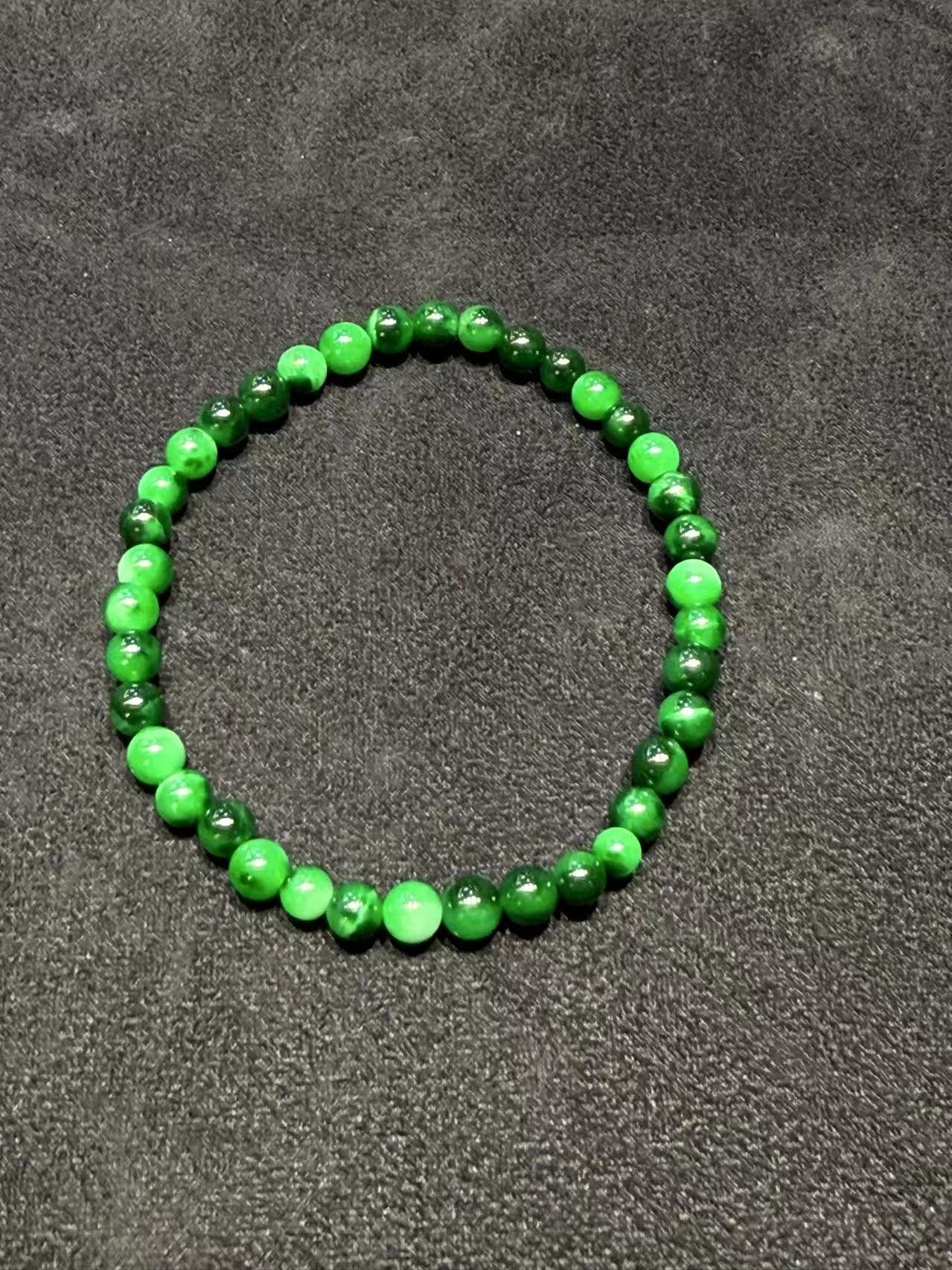 Translucent old pit green jadeite beads bracelet with natural Burmese jade in mixed green tones.