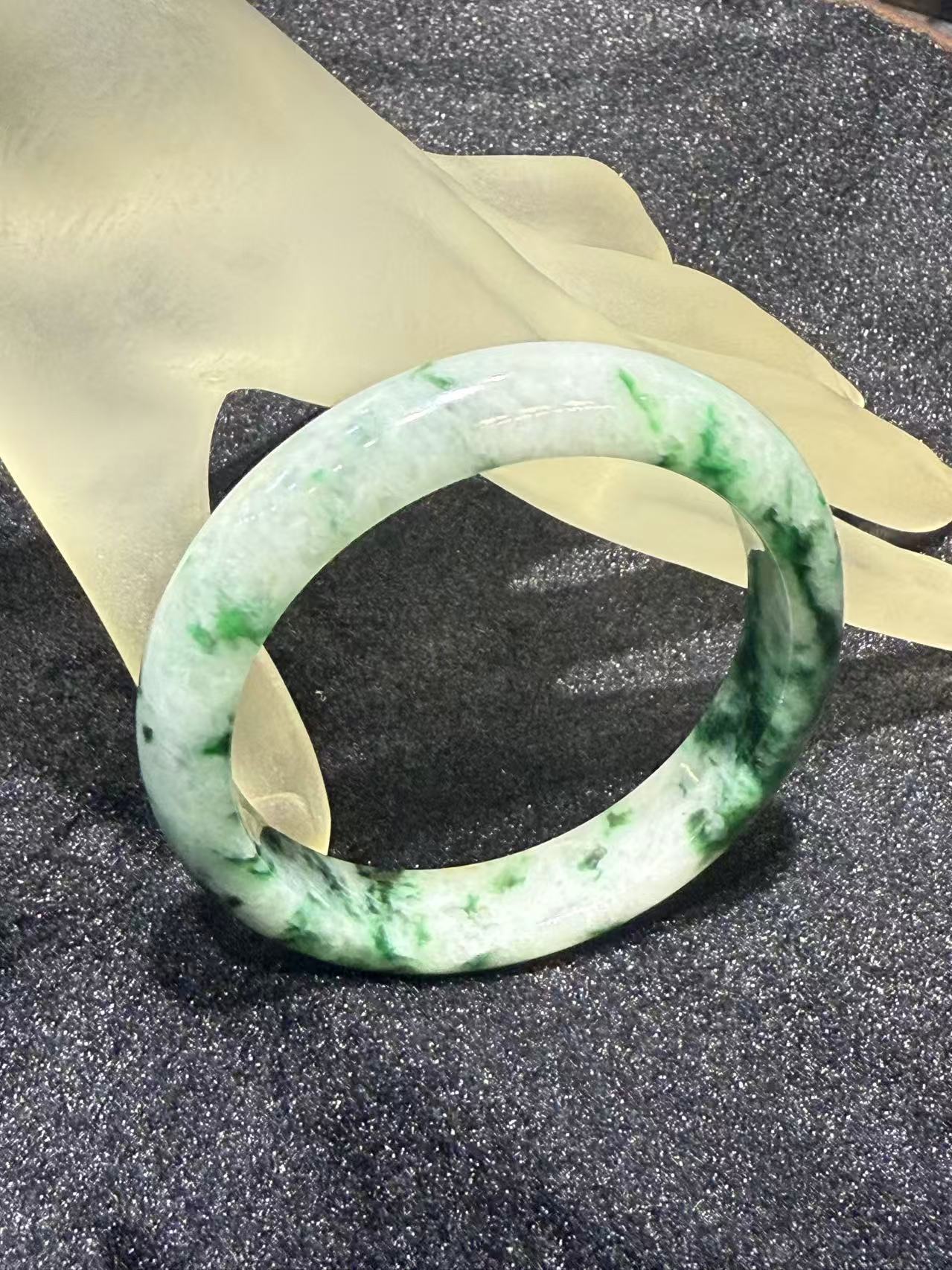 Translucent white jadeite bangle with natural green patterns