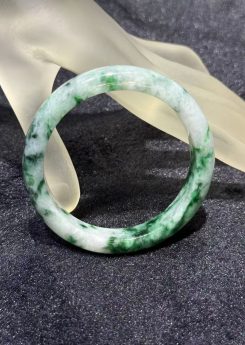 Translucent white jadeite bangle with natural green patterns