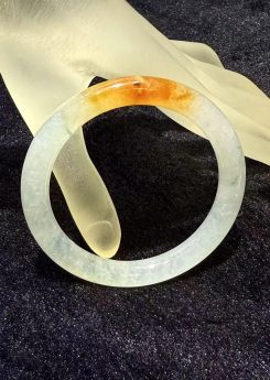 Highly translucent icy jadeite bangle with natural reddish patch