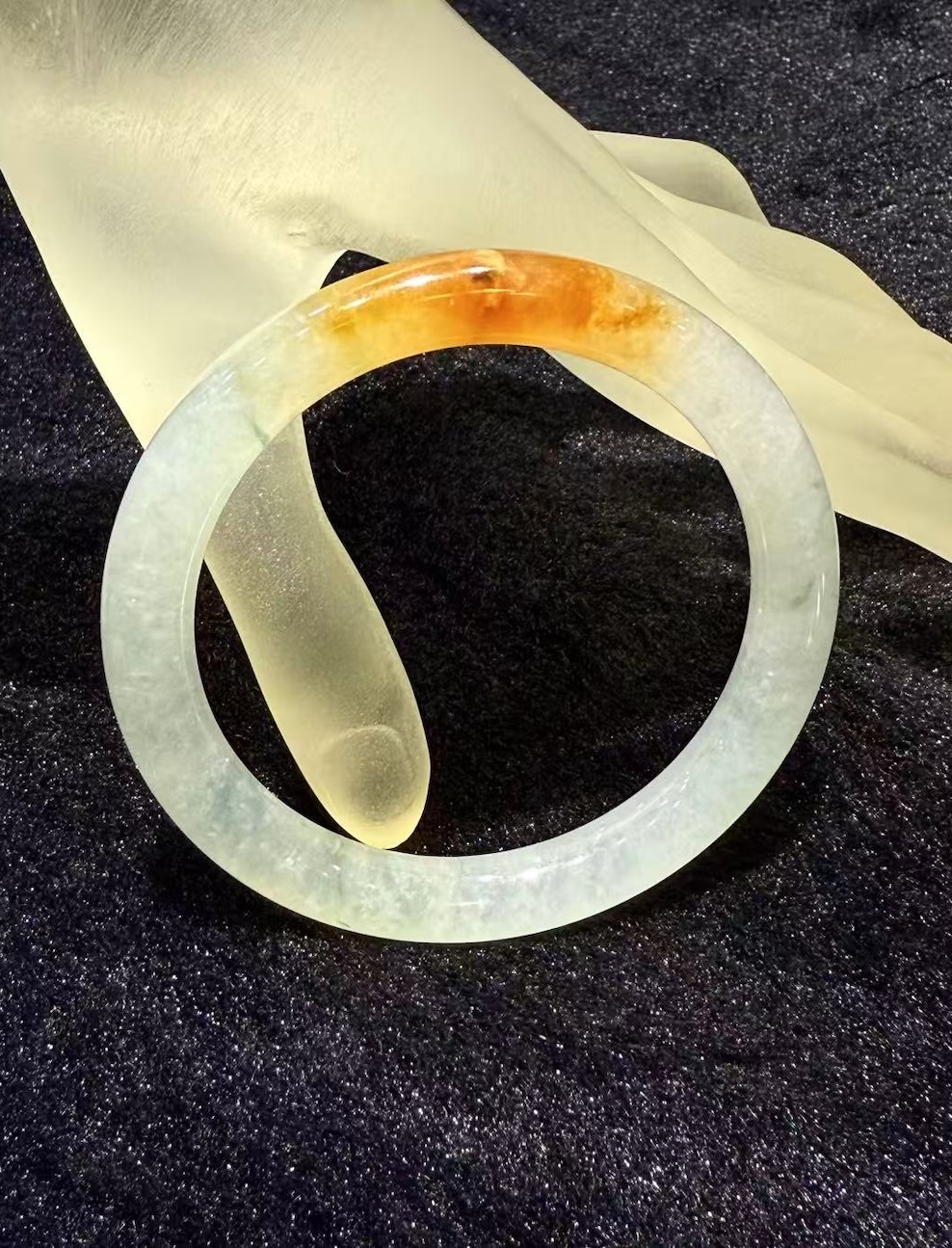 Highly translucent icy jadeite bangle with natural reddish patch