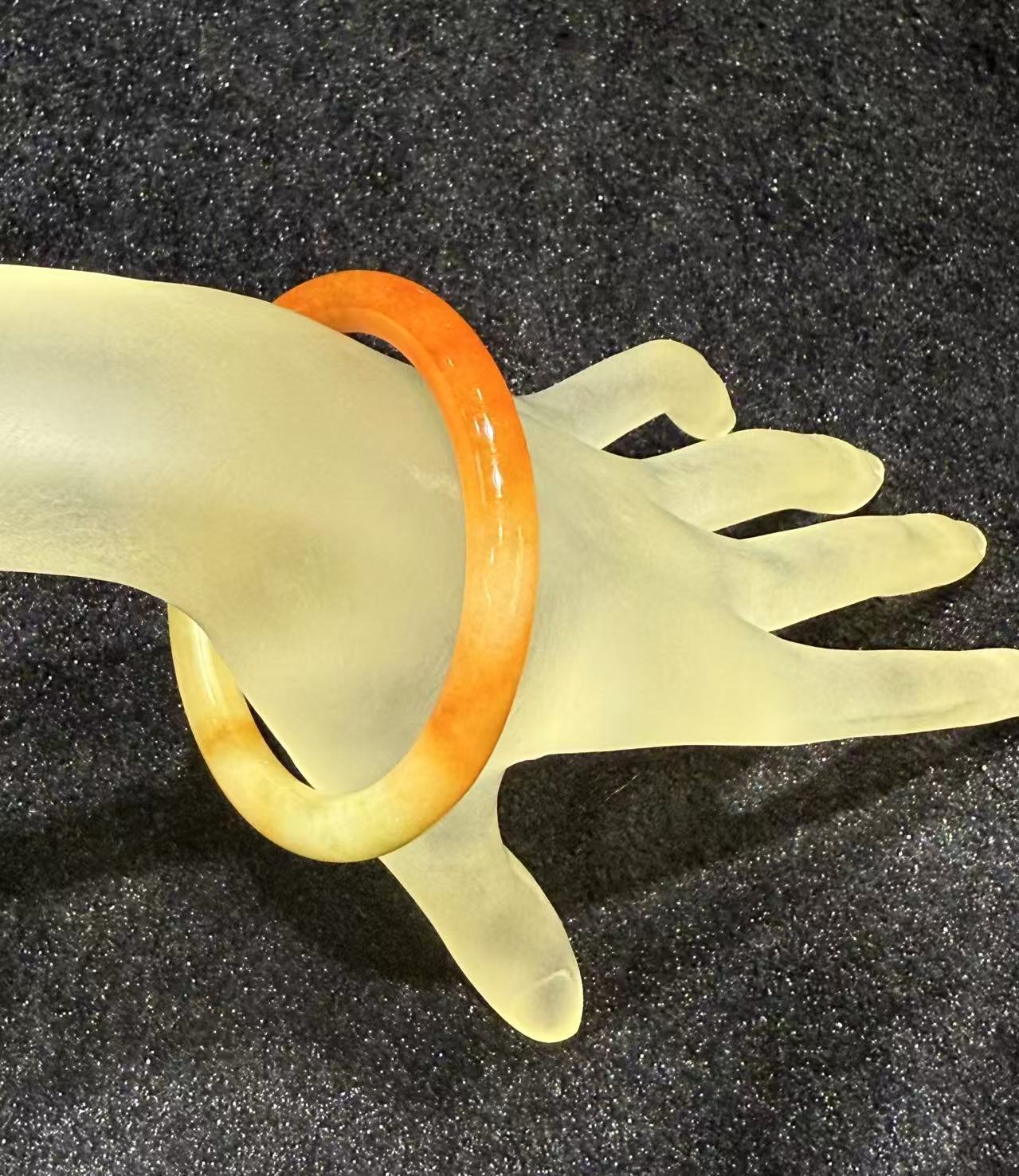 Translucent orange red jadeite bangle with natural colour gradient in classic round cut