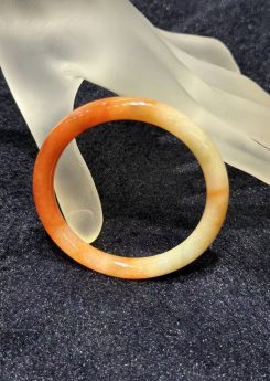 Translucent orange red jadeite bangle with natural colour gradient in classic round cut
