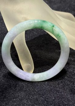 Translucent lavender jadeite bangle with natural green inclusions in classic round cut