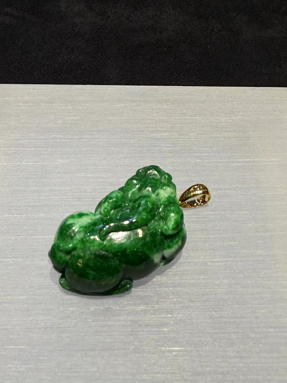 Vibrant green jadeite Pixiu pendant with detailed carving and gold bail