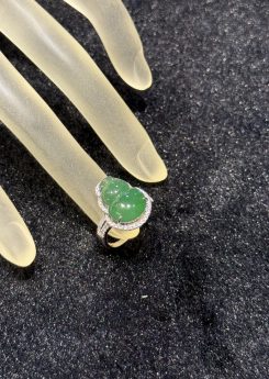 Jade gourd ring carved from icy translucent dark green jadeite, set in 18k white gold with a diamond halo and diamond-set shoulders