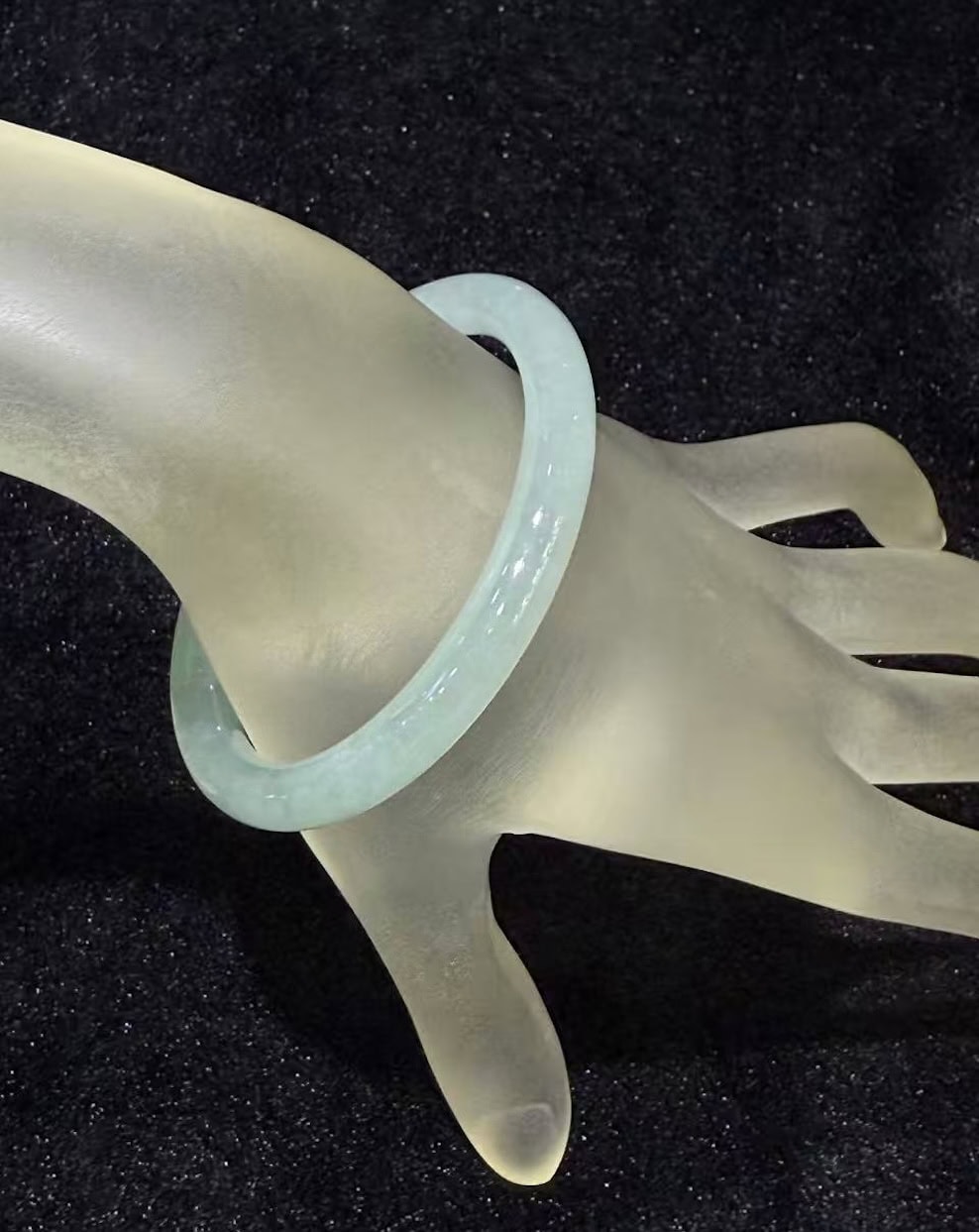 Icy jadeite bangle with a highly translucent body and a faint green wash, carved in a round cut from a single piece of jade
