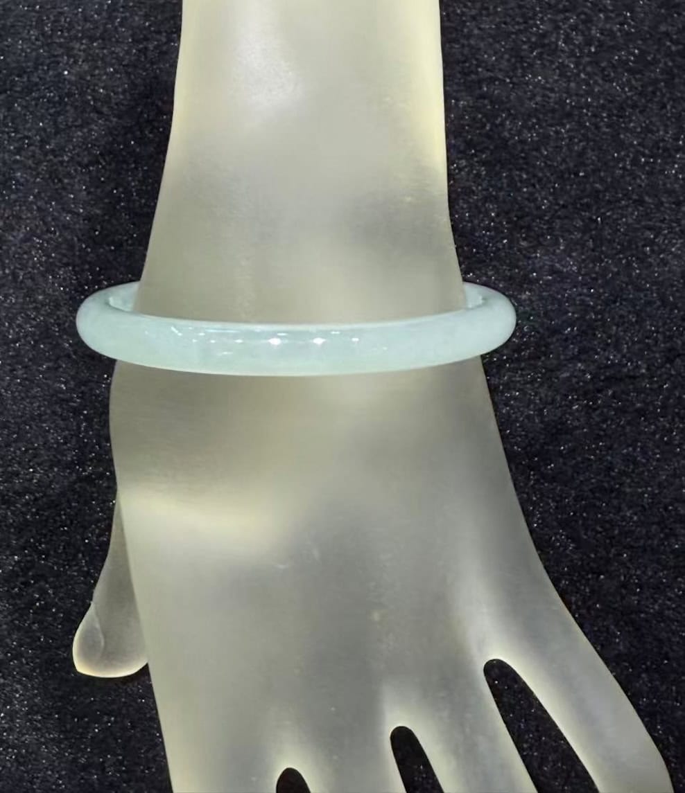 Icy jadeite bangle with a highly translucent body and a faint green wash, carved in a round cut from a single piece of jade