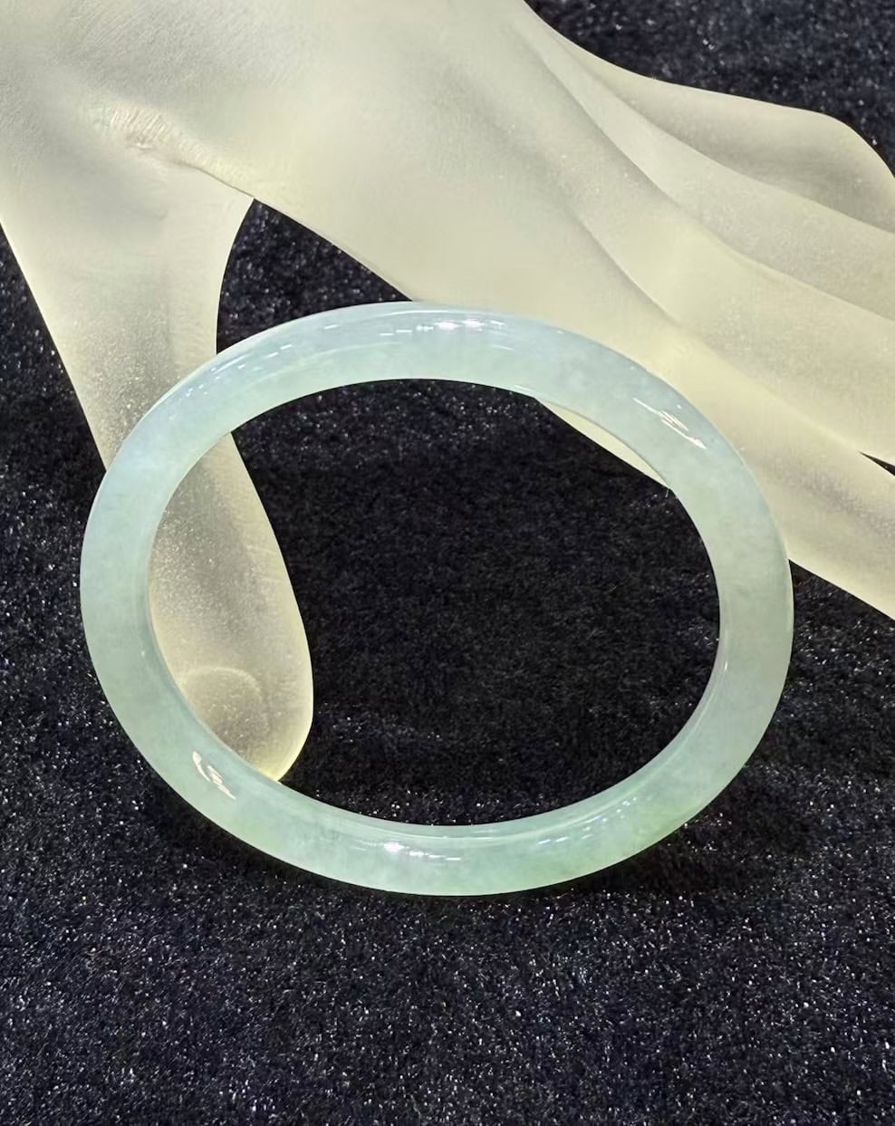 Icy jadeite bangle with a highly translucent body and a faint green wash, carved in a round cut from a single piece of jade