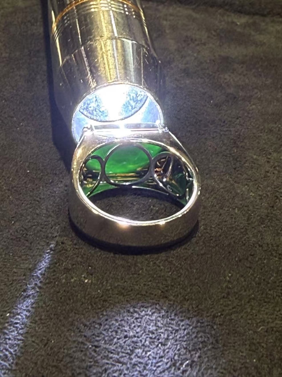 Black jade ring with a saddle-shaped omphacite cabochon that reads pure black under normal light, set in a polished 18k white gold band