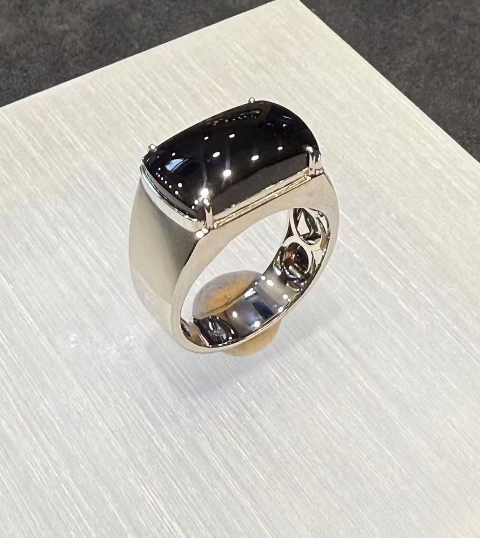 Black jade ring with a saddle-shaped omphacite cabochon that reads pure black under normal light, set in a polished 18k white gold band