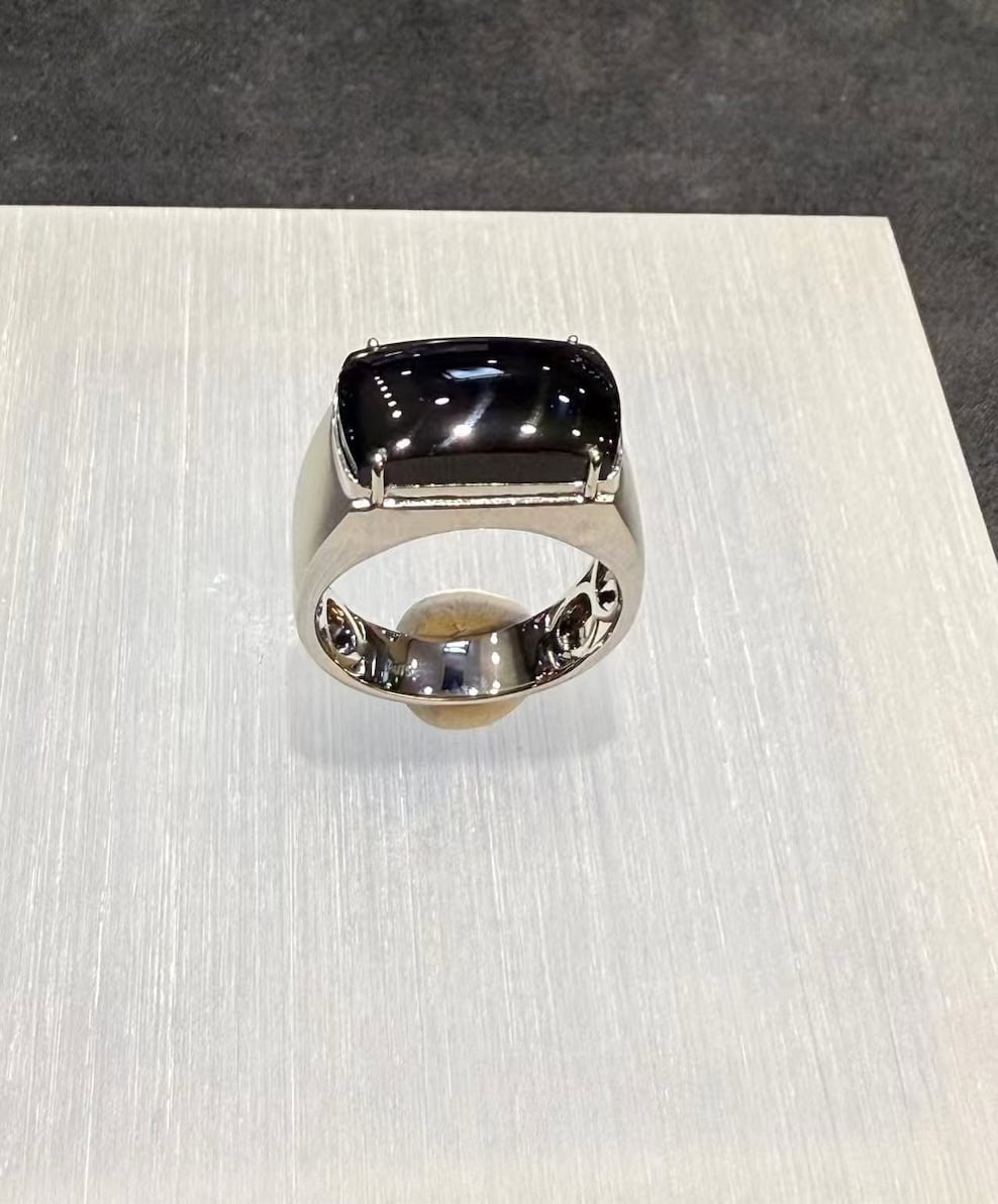 Black jade ring with a saddle-shaped omphacite cabochon that reads pure black under normal light, set in a polished 18k white gold band