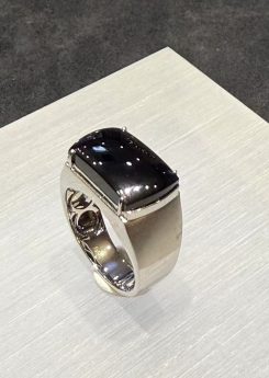 Black jade ring with a saddle-shaped omphacite cabochon that reads pure black under normal light, set in a polished 18k white gold band