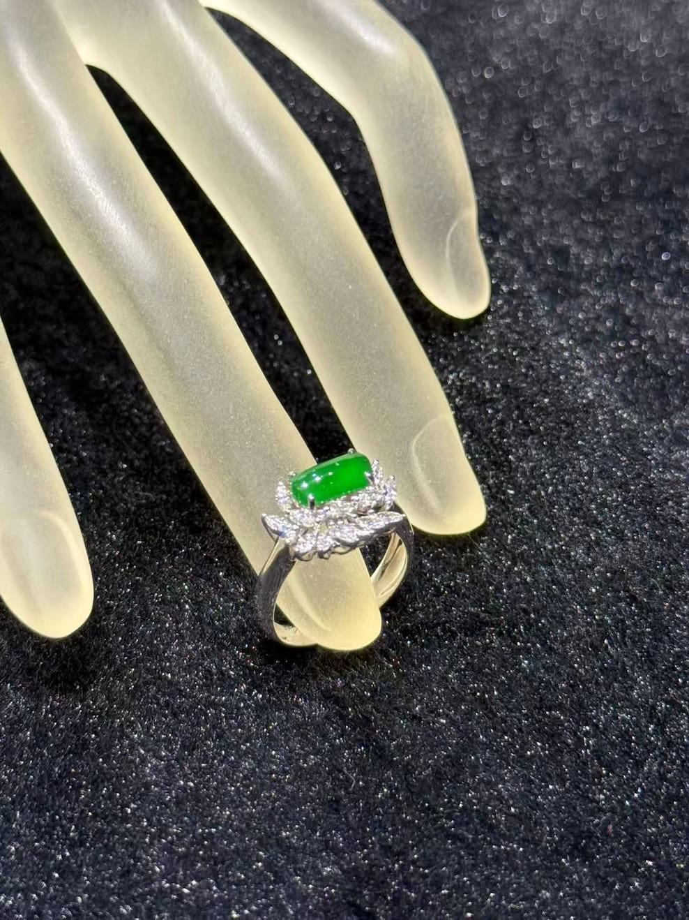 Green jadeite ring with a vivid, almost translucent saddle-shaped cabochon, set in 18k white gold below a fan of marquise-cut diamonds