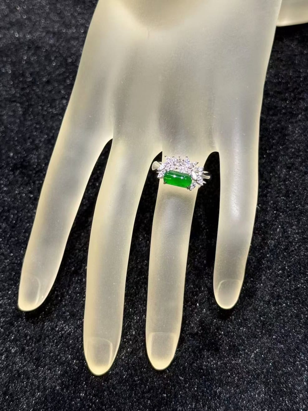 Green jadeite ring with a vivid, almost translucent saddle-shaped cabochon, set in 18k white gold below a fan of marquise-cut diamonds