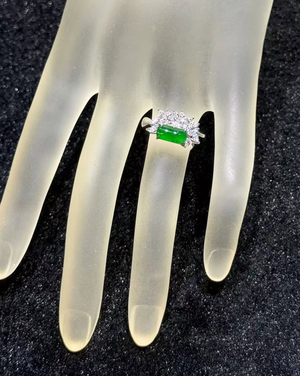 Green jadeite ring with a vivid, almost translucent saddle-shaped cabochon, set in 18k white gold below a fan of marquise-cut diamonds