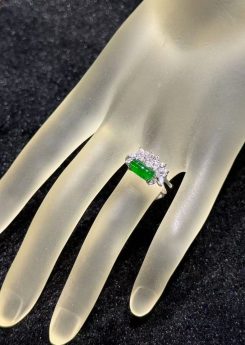 Green jadeite ring with a vivid, almost translucent saddle-shaped cabochon, set in 18k white gold below a fan of marquise-cut diamonds