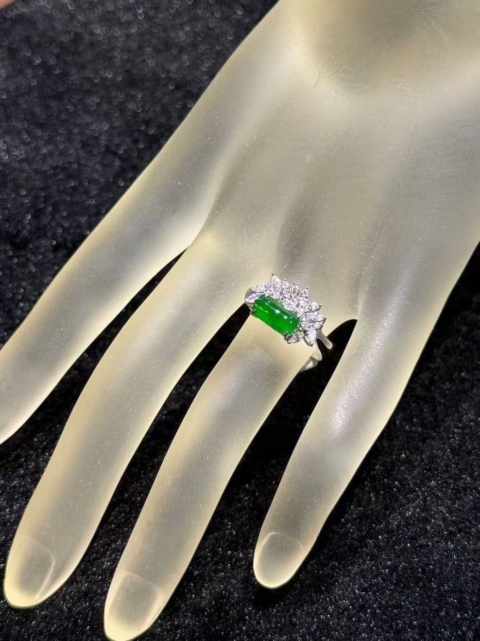 Green jadeite ring with a vivid, almost translucent saddle-shaped cabochon, set in 18k white gold below a fan of marquise-cut diamonds