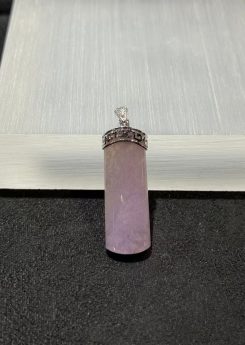 Lavender jade pendant shaped as a smooth uncarved jadeite cylinder, set in 18k white gold with a diamond bail and fretwork cap, displayed on a white stand