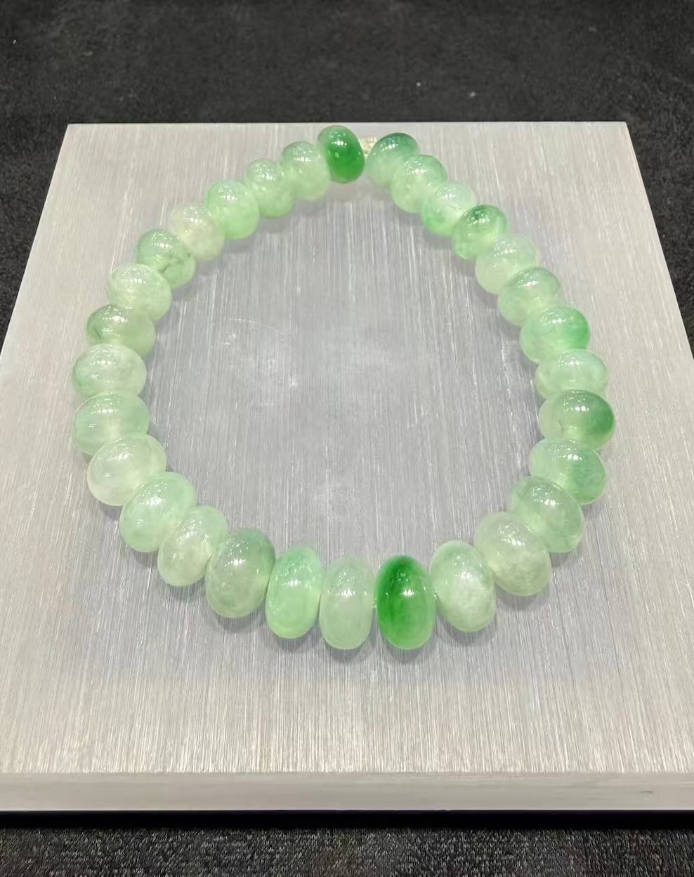 Jadeite abacus bracelet of icy, translucent jadeite beads with patches of vibrant green floating across the strand