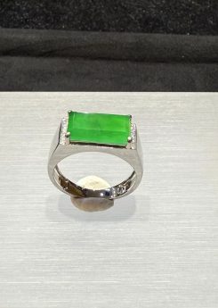 Men's jade ring set with an icy, translucent vibrant green rectangular jadeite cabochon, framed by small diamonds in a wide 18k white gold band
