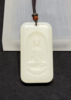 Guanyin nephrite pendant carved from soft white colour, showing the seated Bodhisattva on a lotus within a rectangular pai-zi plaque with a cloud-pattern border, on a black cord