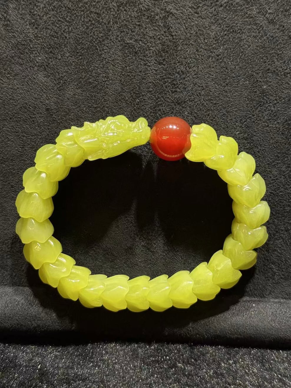 Yellow nephrite bracelet carved as a coiled dragon, with a detailed dragon head and scale-carved body, paired with a small red agate pearl bead