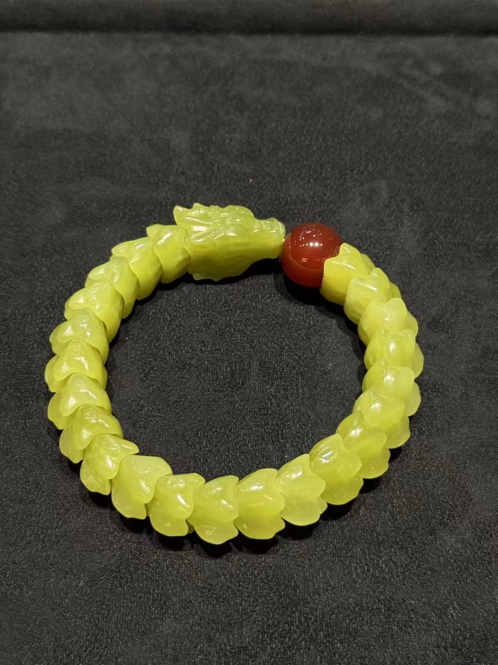 Yellow nephrite bracelet carved as a coiled dragon, with a detailed dragon head and scale-carved body, paired with a small red agate pearl bead