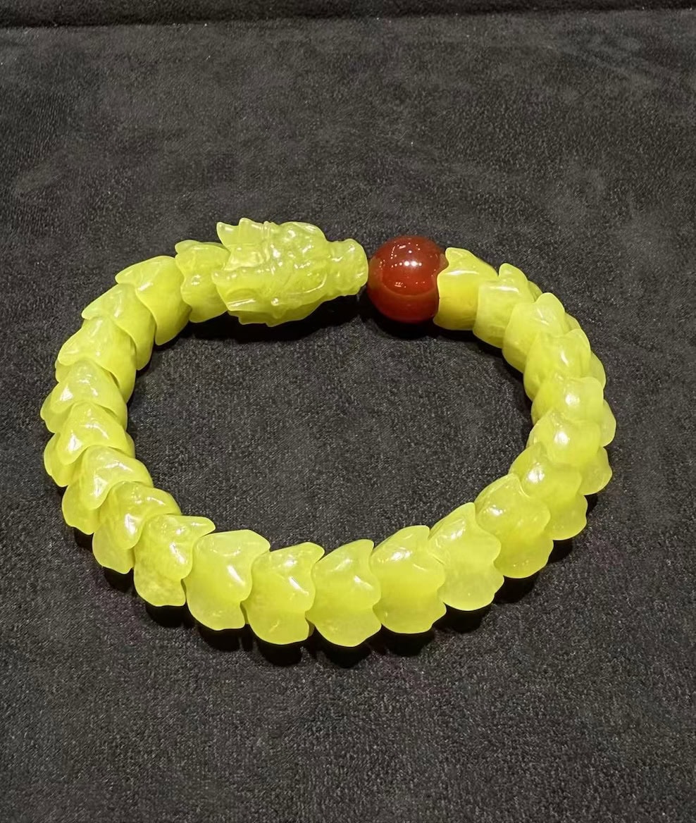 Yellow nephrite bracelet carved as a coiled dragon, with a detailed dragon head and scale-carved body, paired with a small red agate pearl bead
