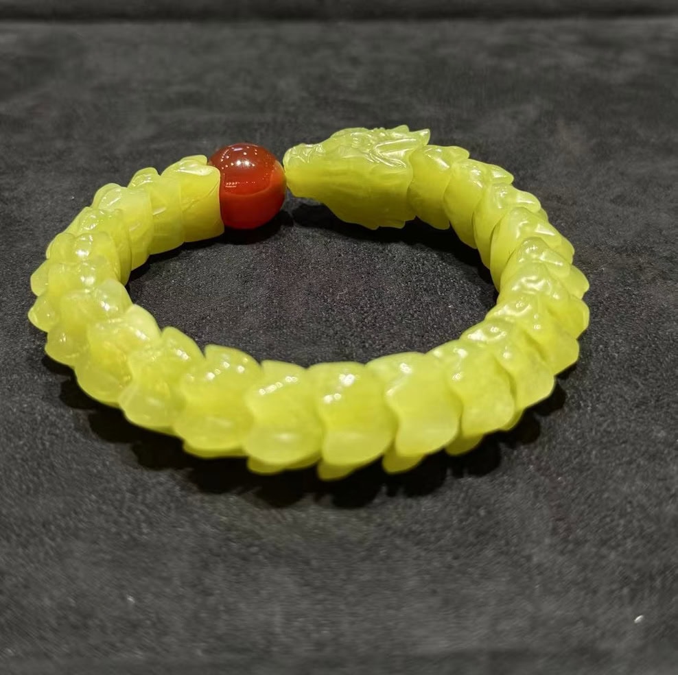 Yellow nephrite bracelet carved as a coiled dragon, with a detailed dragon head and scale-carved body, paired with a small red agate pearl bead