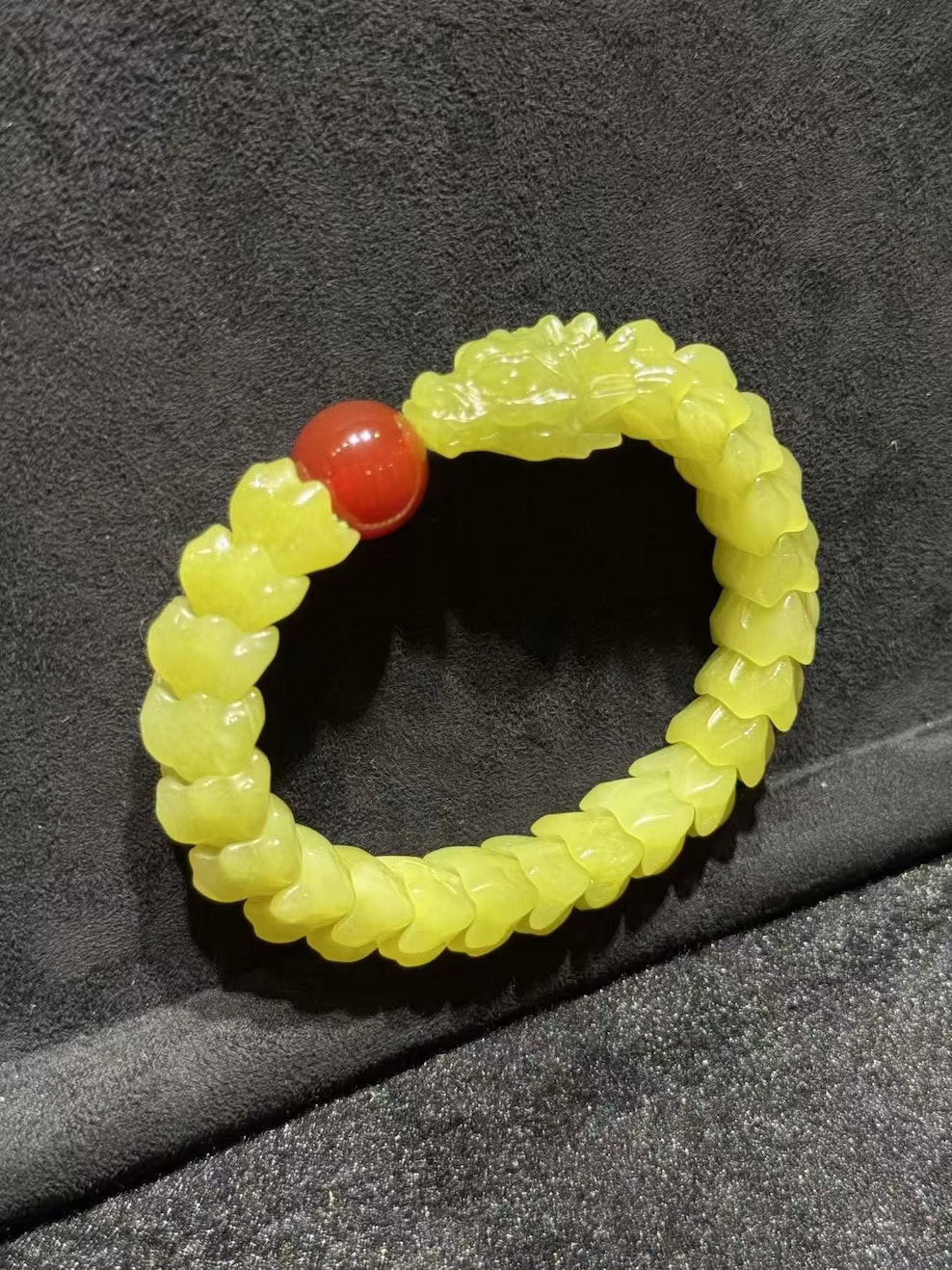 Yellow nephrite bracelet carved as a coiled dragon, with a detailed dragon head and scale-carved body, paired with a small red agate pearl bead