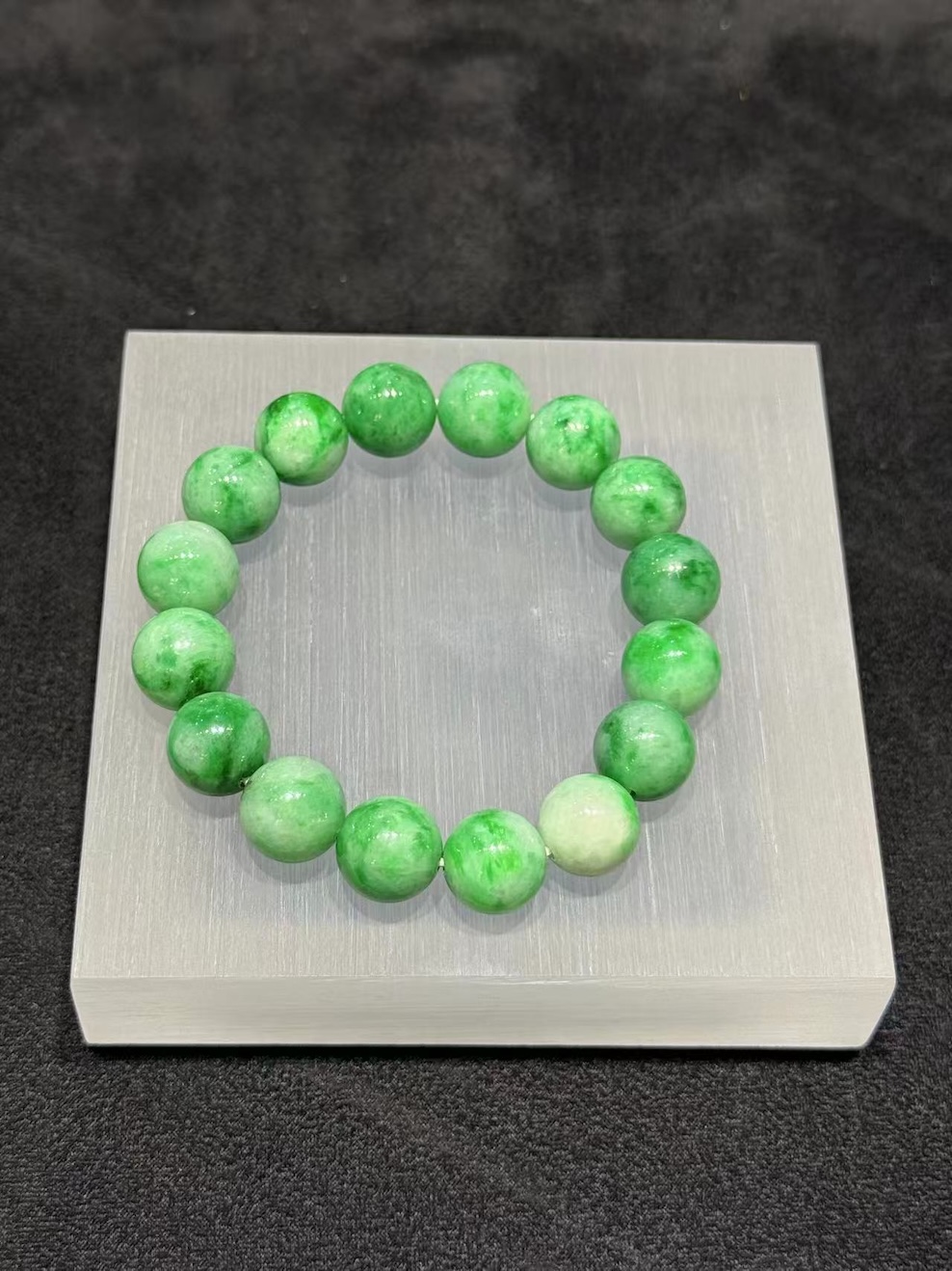 Apple green jadeite bracelet strung with round translucent vibrant apple-green jadeite beads, showing natural light and deeper green patches