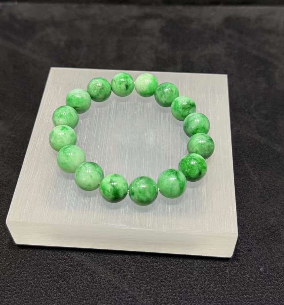 Apple green jadeite bracelet strung with round translucent vibrant apple-green jadeite beads, showing natural light and deeper green patches