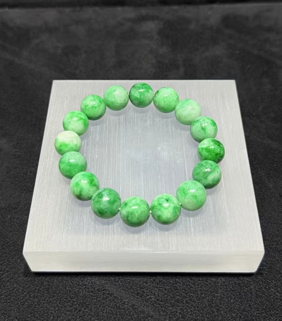 Apple green jadeite bracelet strung with round translucent vibrant apple-green jadeite beads, showing natural light and deeper green patches