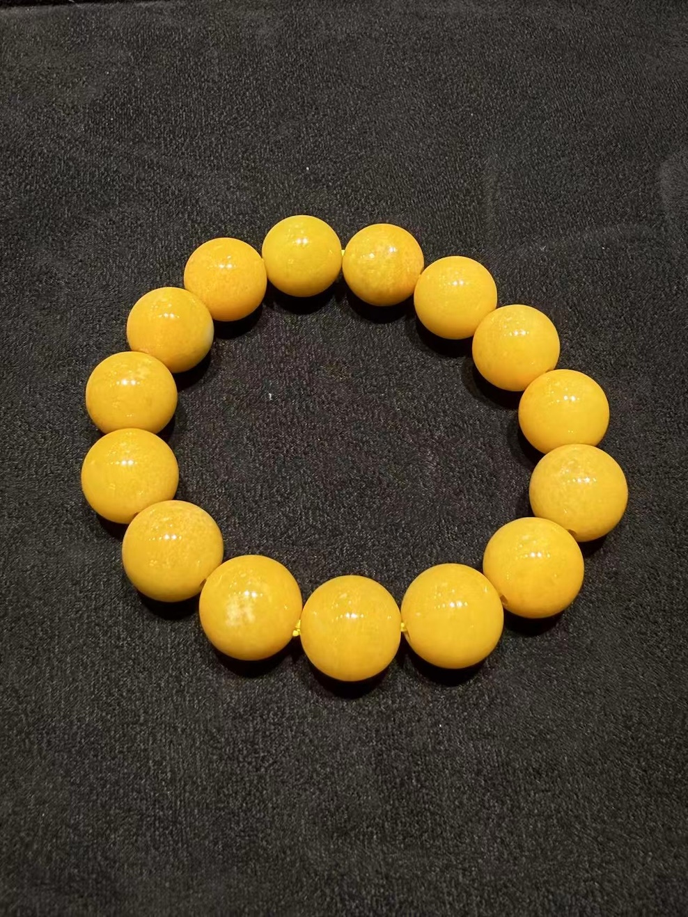 Honey jade bracelet strung with round translucent vibrant honey-yellow jadeite beads in a warm, even golden tone