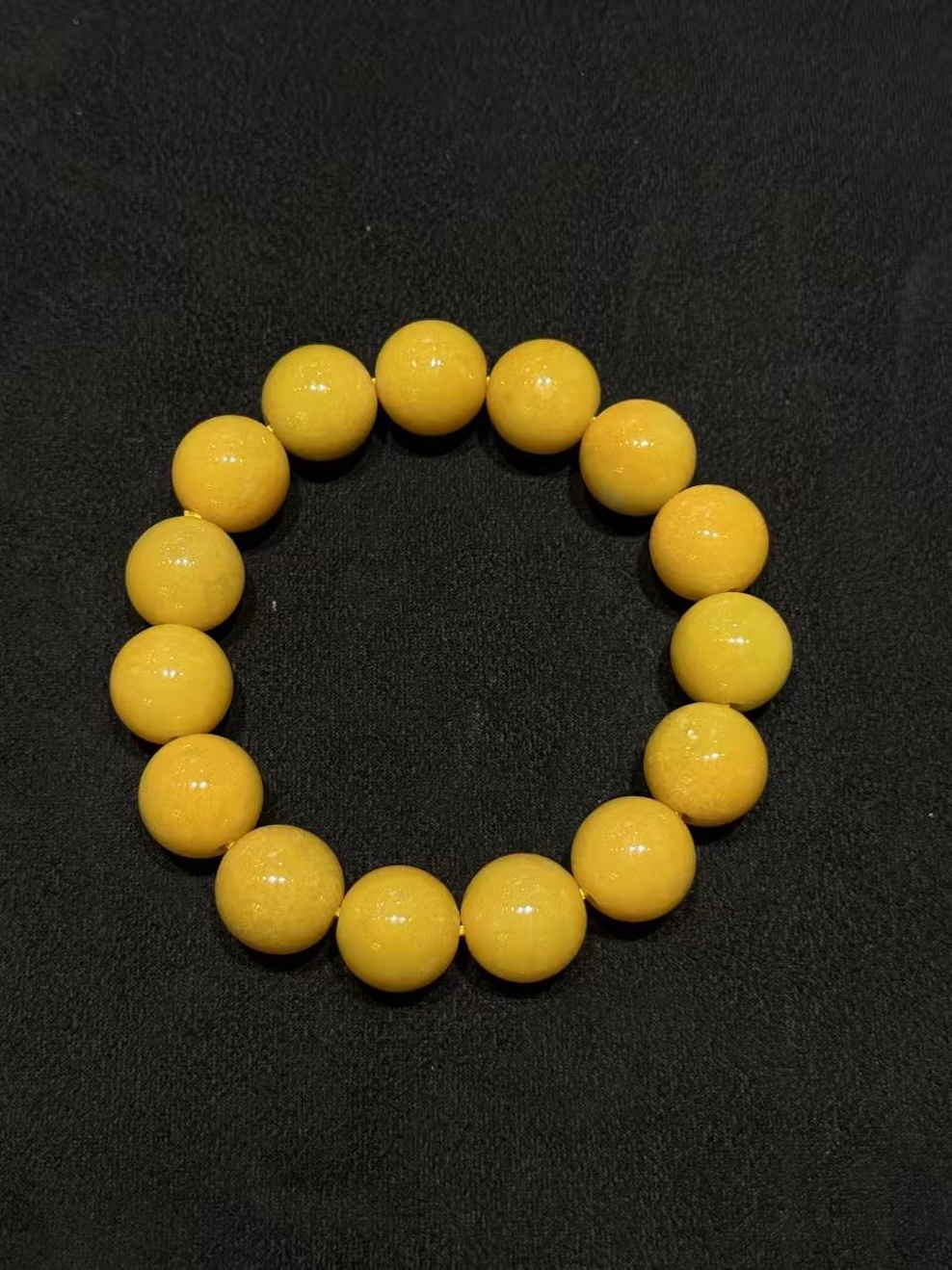 Honey jade bracelet strung with round translucent vibrant honey-yellow jadeite beads in a warm, even golden tone