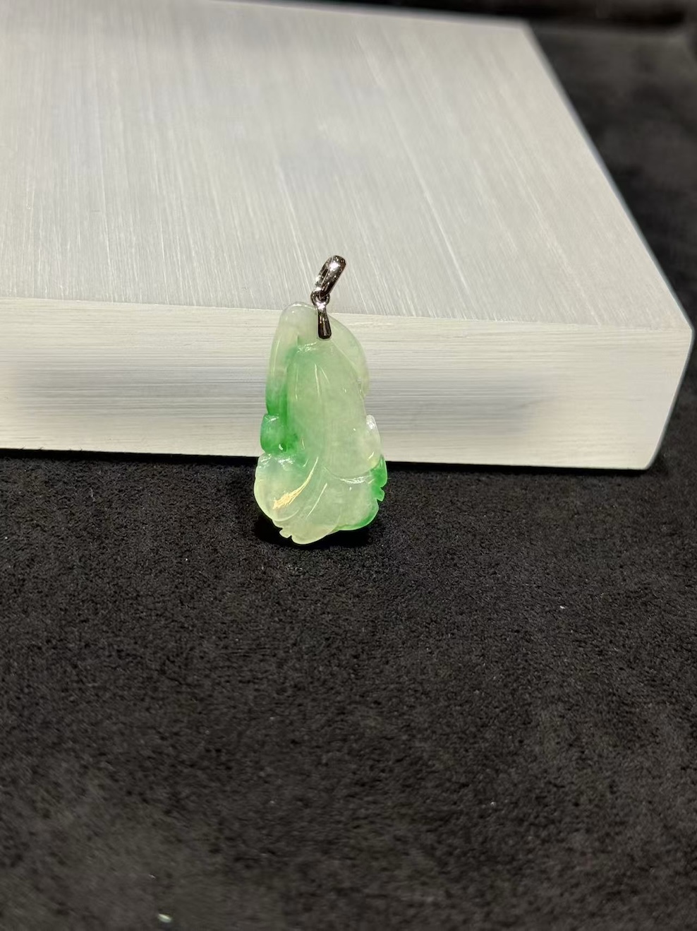 Ruyi jade pendant carved from translucent icy white and vibrant green jadeite, with a curling ruyi head and small flower bud details, hung from a 18k white gold bail