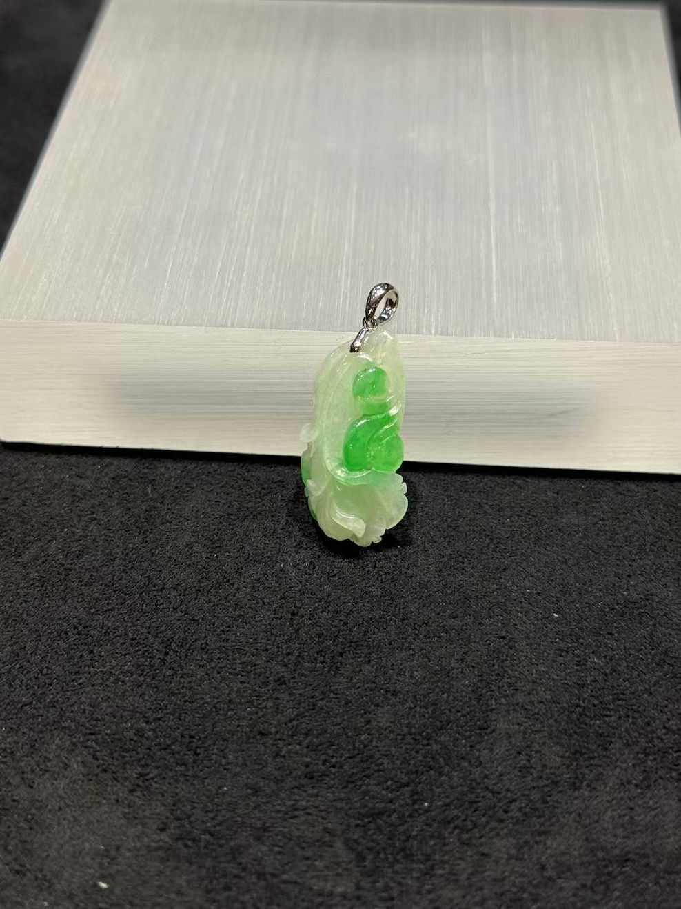 Ruyi jade pendant carved from translucent icy white and vibrant green jadeite, with a curling ruyi head and small flower bud details, hung from a 18k white gold bail