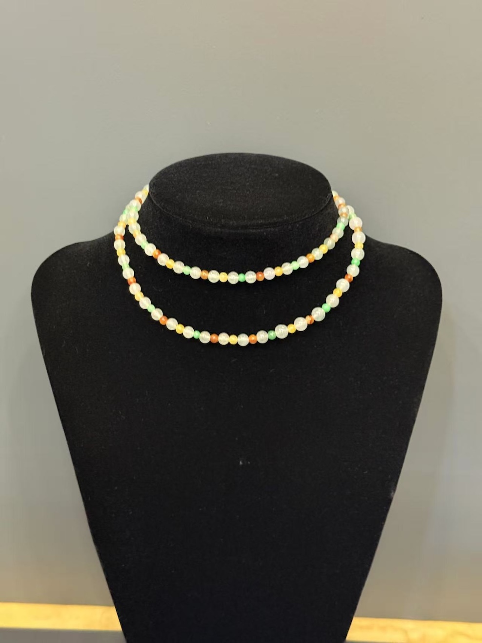 Multi-colour jadeite necklace strung with icy translucent jadeite beads and smaller vibrant green, yellow, and orange-red jade spacer beads