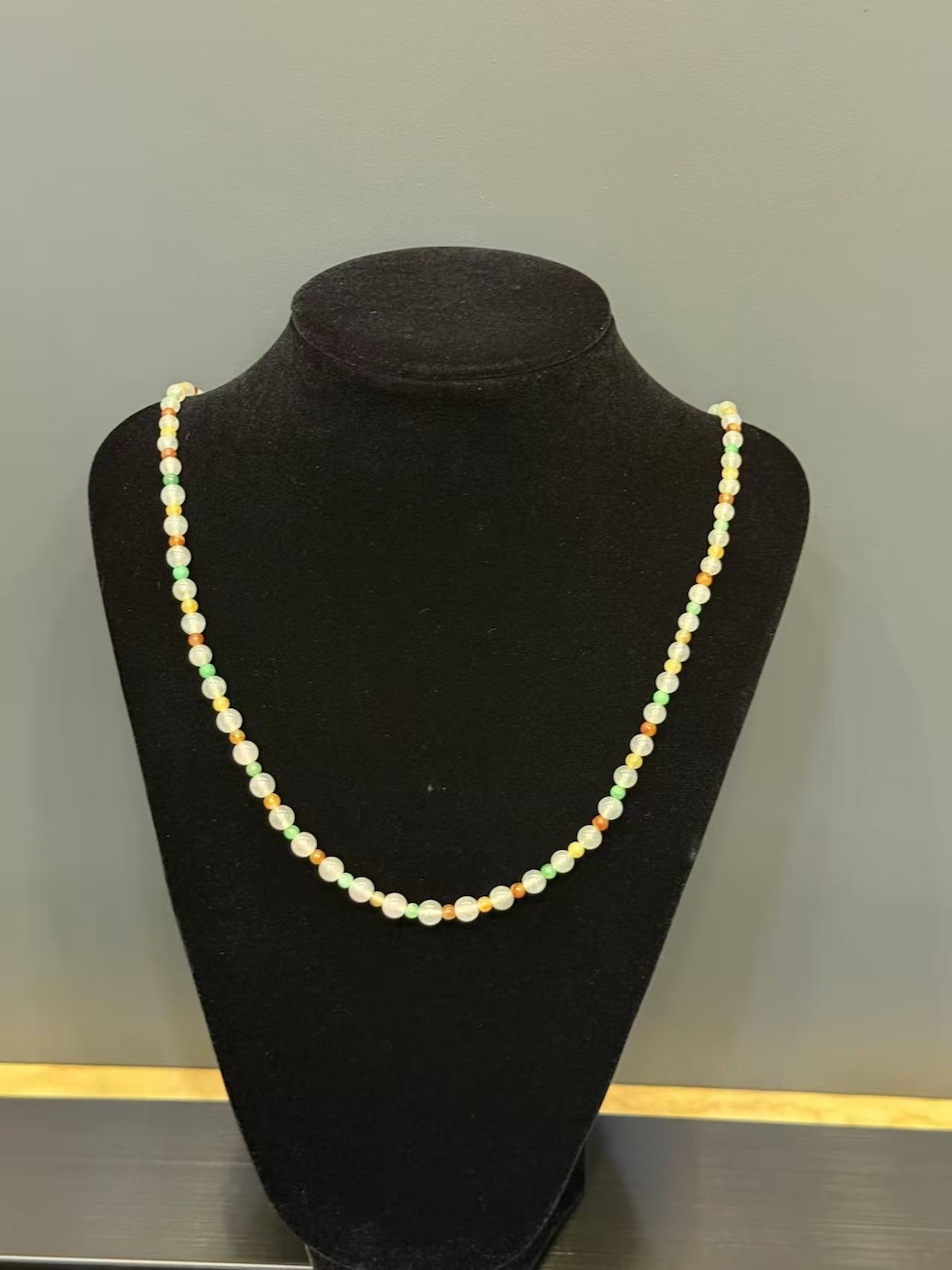 Multi-colour jadeite necklace strung with icy translucent jadeite beads and smaller vibrant green, yellow, and orange-red jade spacer beads