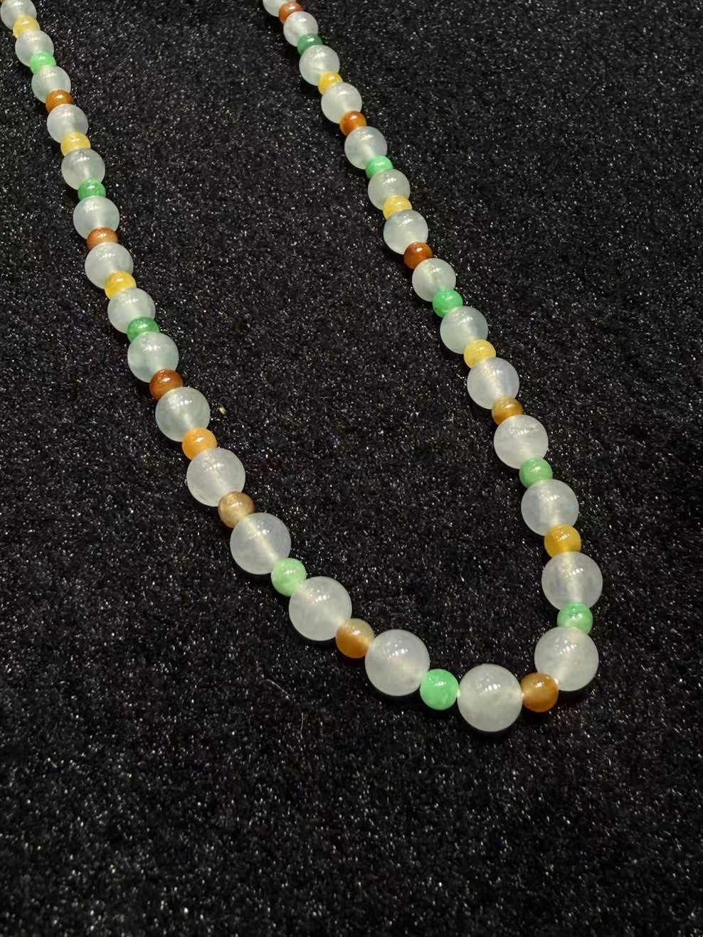 Multi-colour jadeite necklace strung with icy translucent jadeite beads and smaller vibrant green, yellow, and orange-red jade spacer beads
