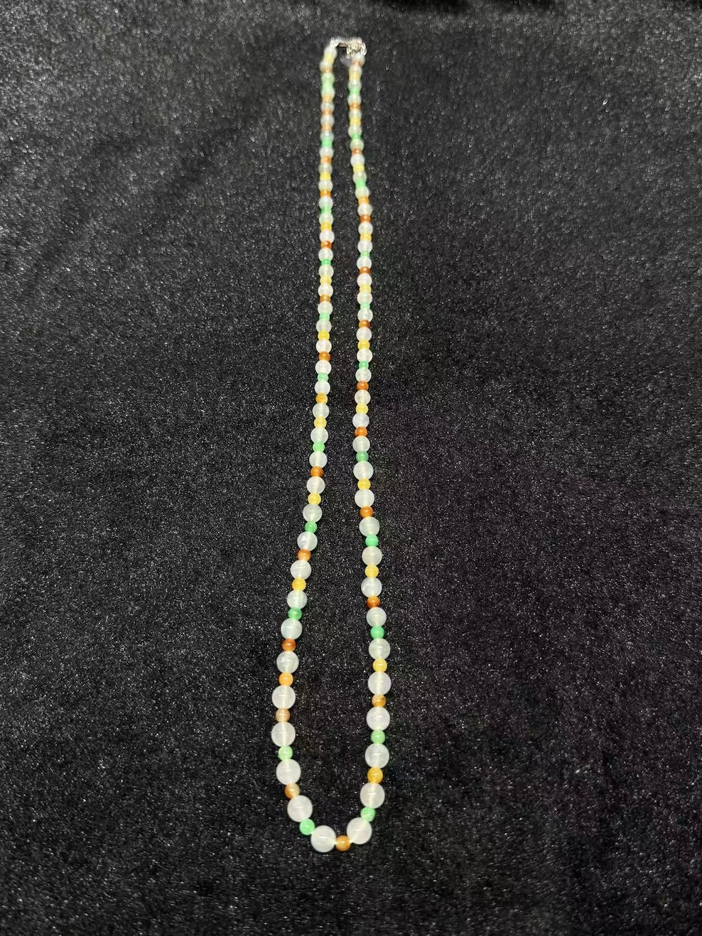 Multi-colour jadeite necklace strung with icy translucent jadeite beads and smaller vibrant green, yellow, and orange-red jade spacer beads